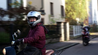Die Stuttgarter Pfarrerin Vinh An Vu fährt auf ihrer Vespa. Sie trägt einen Motorradhelm.