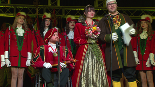 Eine Fasnet-Gesellschaft. Die Fasnetsprinzessin steht neben dem Fasnetsprinzen. Er sitzt im Rollstuhl.