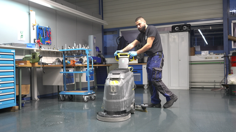 Ein junger Mann schiebt eine Reinigungsmaschine.