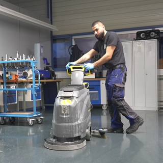 Ein junger Mann schiebt eine Reinigungsmaschine.