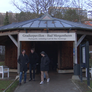 Drei Männer laufen aus einem Pavillon im Kurgarten. 