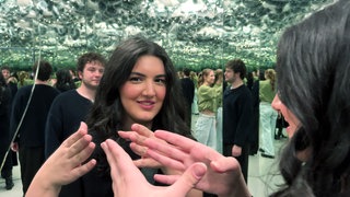 Eine junge Frau steht vor einem Spiegel im Museum der Illusionen in Stuttgart.