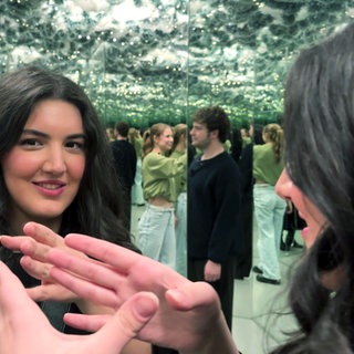 Eine junge Frau steht vor einem Spiegel im Museum der Illusionen in Stuttgart.