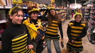 4 Frauen stehen in schwarz-gelber Kleidung im Supermarkt