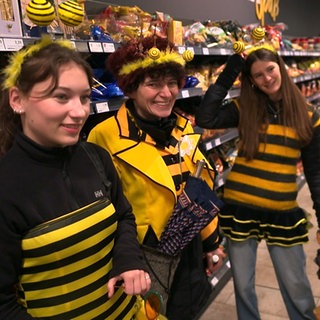 4 Frauen stehen in schwarz-gelber Kleidung im Supermarkt