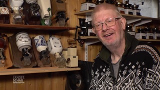 Günter Fiebelkorn steht neben Regalbrettern voller Kaffeemühlen