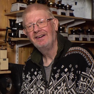 Günter Fiebelkorn steht neben Regalbrettern voller Kaffeemühlen