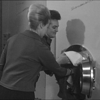 Waschsalon in den 60er Jahren. Ein Paar befüllt die Waschmaschine.