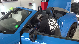 Ein Mitarbeiter von Daniel Kampmann reinigt ein blaues Auto in der Werkstatt.