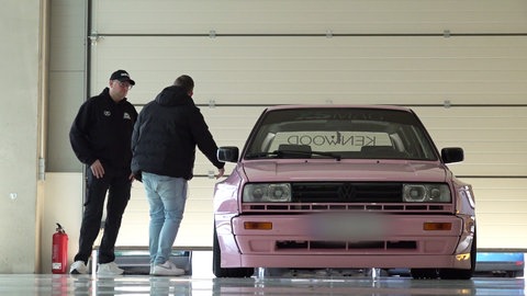 Daniel Kampmann mit Kunden stehen neben einem pinken VW.