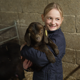 Die neunjährige Enna hat eine Babyziege auf dem Arm.