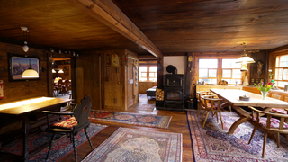 Die Stube des Wildenhofs. Ein rustikal möblierter Raum mit vielen Teppichen. 