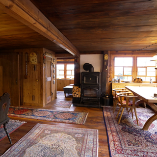Die Stube des Wildenhofs. Ein rustikal möblierter Raum mit vielen Teppichen. 