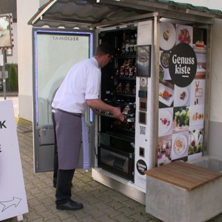 Ein Koch steht vor dem geöffneten Automaten vor dem Restaurant Storchen in Schmidhofen.