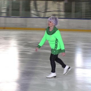 Bobi Frydrych trägt einen neongrünen Anzug und läuft mit Schlittschuhen über das Eis der Eishalle Pforzheim.