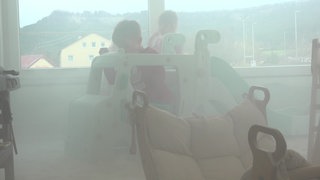 Zwei Kinder spielen auf einer Mini-Rutsche in einem dampfgefüllten Raum.