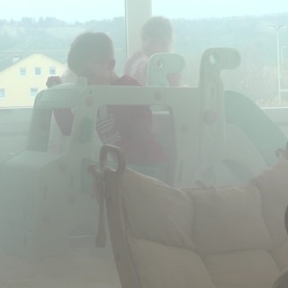 Zwei Kinder spielen auf einer Mini-Rutsche in einem dampfgefüllten Raum.