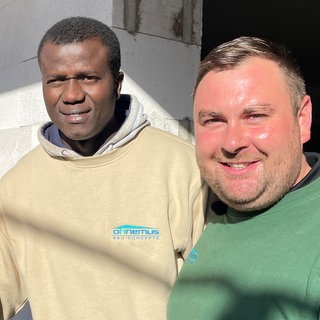 Steven Eckardt, Lamin Jaiteh und Leon Ohnemus machen ein Selfie vor einer Sandsteinwand.