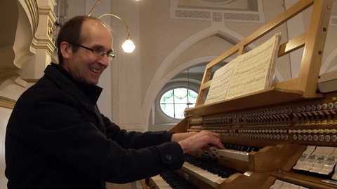 Kantor Christoph Kuppler spielt die Orgel und lächelt dabei.