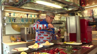 Rino Bernardi steht in seiner Eisdiele in Ochsenhausen und bereitet Eisbecher zu.
