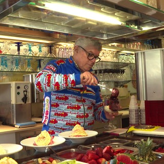 Rino Bernardi steht in seiner Eisdiele in Ochsenhausen und bereitet Eisbecher zu.