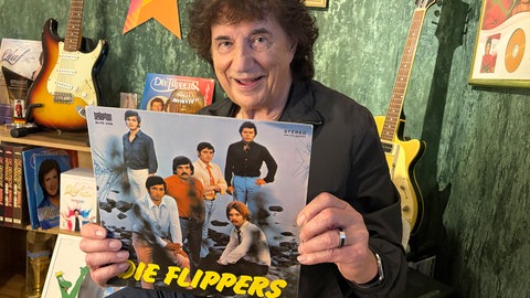 Olaf der Flipper hält eine Schallplattenhülle mit der Aufschrift "Die Flippers" in die Kamera.