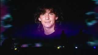 Eine Projektion eines jungen Thomas Anders läuft auf einer Leinwand. Im Vordergrund erkennt man die Silhouetten einer Band.