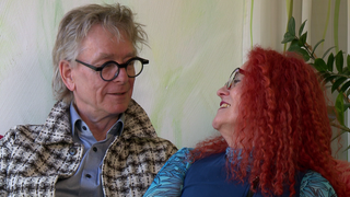 Diana Zöller und Edzard Schoppmann sitzen nah beieinander und lächeln. 