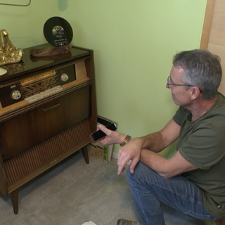 Peter Keßner kniet vor einer alten Musiktruhe.