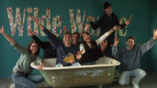 Drei Erzieherinnen und fünf Erzieher haben sich um und in einer Wanne versammelt. Sie recken die Arme in die Luft. Ein Schriftzug „Wilde Wanne“ ist im Hintergrund.