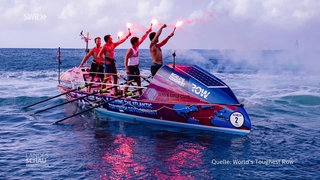 Vier Männer auf einem großen Ruderboot halten Leuchfackeln in der Hand