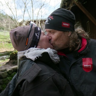 Carolin Engler und Michael Roupp stehen draußen vor einem Käfig und küssen sich.
