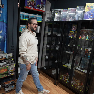 Zwei Männer laufen durch einen Laden. Überall im Hintergrund sind Retro-Spiele und Retro-Konsolen. 