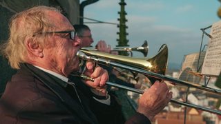 Rolf Klostermann ist 89 Jahre alt. Er steht mit anderen Posaunenspielern auf einem Kirchturm. 