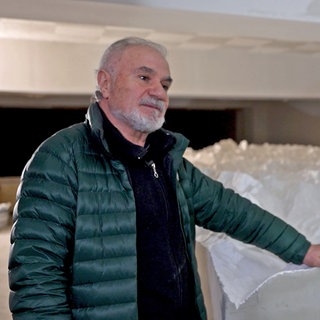 Panos Avramidis steht vor seiner weißen 3D-Nachbildung des Himalayas. Er trägt eine grüne Jacke und hält eine Hand auf der Nachbildung.