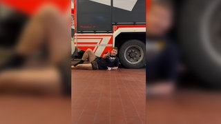 Ein Feuerwehrmann der Feuerwehr Maichingen liegt auf dem Boden und trägt eine Leoparden-Unterhose. Er zeigt in die Kamera.