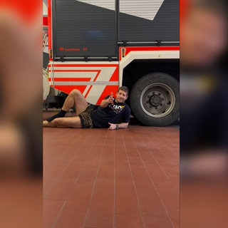 Ein Feuerwehrmann der Feuerwehr Maichingen liegt auf dem Boden und trägt eine Leoparden-Unterhose. Er zeigt in die Kamera.