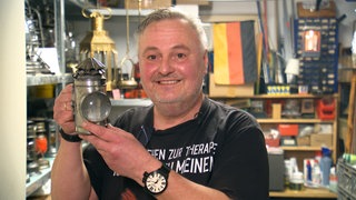 Jürgen Flieger steht mit einer Petroleumlampe in der Hand stolz vor der Kamera.