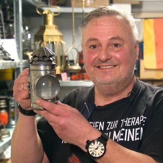 Jürgen Flieger steht mit einer Petroleumlampe in der Hand stolz vor der Kamera.