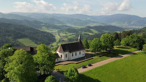 Kirche in einer grünen, ländlichen Landschaft.