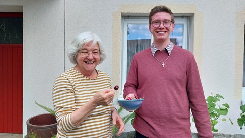 Margit und Oliver essen Kirschen und lächeln in die Kamera.