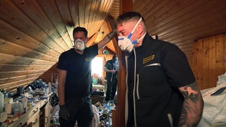 Entrümpler Raphael Uhland und Dejan Čakalo bei ihrer Arbeit in einem Messie-Haus. Sie tragen Masken.