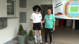 Fußballfan Peter Saß neben einer Puppe in Fußballklamotten.