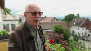 Wolfram Kindl steht auf seinem balkon und grinst.