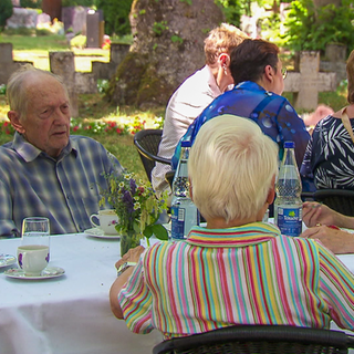 Auf einem Friedhof ist ein Café mit Tischen und Stühlen aufgebaut. 