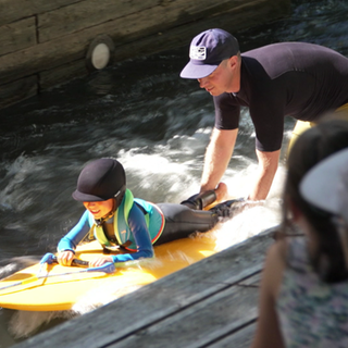 Ein Kind liegt auf einem Surfbrett und surft auf der "blackforestwave in Pforzheim".