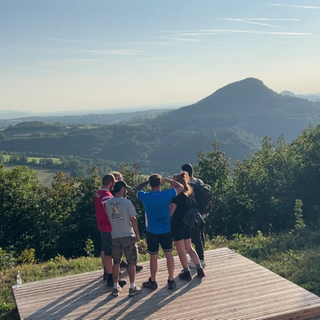 Die Wandergruppe Wandersocken steht auf einer Aussichtsplattform und schaut in die Ferne. Beim gemeinsamen Wandern werden aus Fremden oft Freunde.
