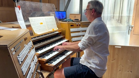 Ein Mann sitzt an der Orgel im Ulmer Münster.