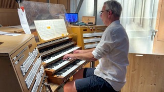 Ein Mann sitzt an der Orgel im Ulmer Münster.