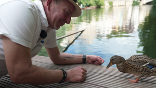 Eine Ente und ein kniender Mann auf einem Floss 